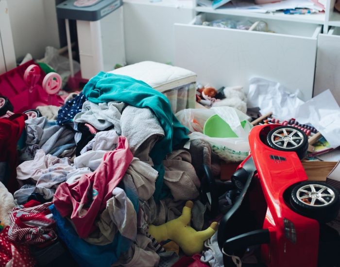 Messy room and disorder concept in the living room or bedroom. Scattered clothes and stuff on the floor.